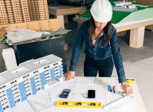 african-american-lady-safety-helmet-standing-near-model-building_23-2148039865