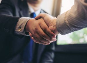 Two business men shaking hands during a meeting to sign agreement and become a business partner, enterprises, companies, confident, success dealing, contract between their firms.